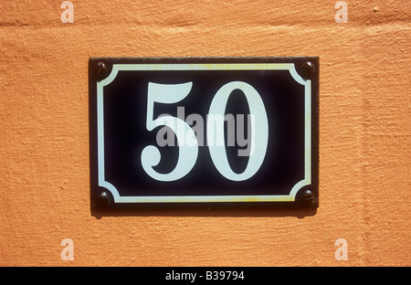 Close up of Continental European style of blue and white enamel house number sign stating 50 on salmon-pink wall Stock Photo