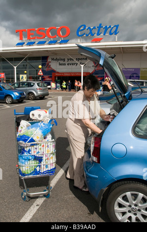 Woman outside Tesco grocery store loading weekly food shopping