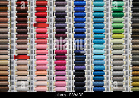 Selection of coloured threads in rack on display in shop one empty space Stock Photo