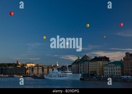 Six sunlit colorful hot air balloons float over Stockholm harbour sightseeing in the city waterfront on a beautiful blue sky summer afternoon Stock Photo