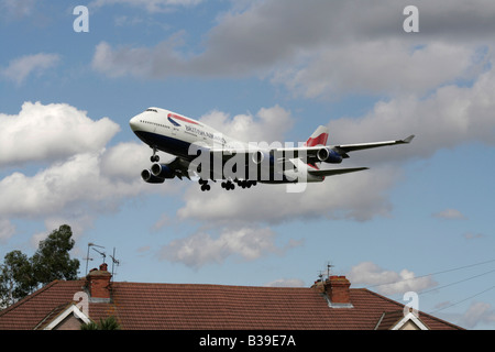 British Airways Boeing 747-400 passenger jet airliner overflies a house while on approach to Heathrow Airport. Civil aviation and noise pollution. Stock Photo