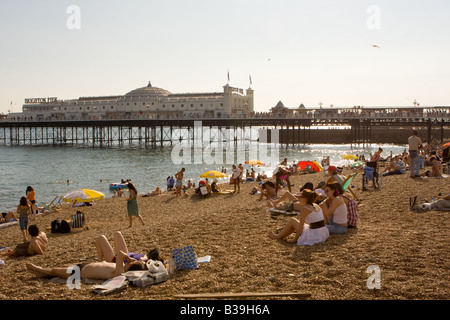 People sunbathing on the beach with Brighton Pier in the background Stock Photo
