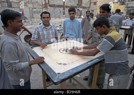 some youths and men at a game of carrom Jugendliche und Männer spielen Carom Stock Photo