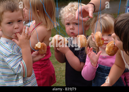 Children eating doughnuts off a string Stock Photo