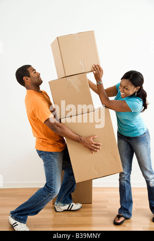 African American female placing boxes on large stack man is holding Stock Photo