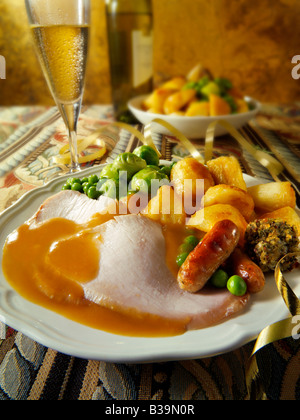 Traditional roast turkey Christmas dinner with all the trimmings and roast potatoes, plated & erved in a festive table  setting Stock Photo