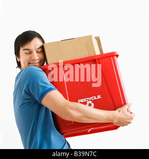 Portrait of smiling Asian young man holding recycling bin Stock Photo