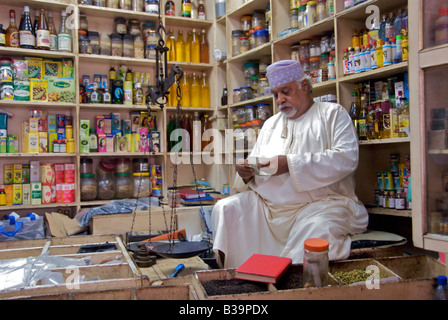 Market trader in shop counting money Old Souq Mutrah Muscat Oman Stock Photo