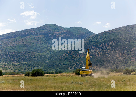 Photo of a large excavator tracked backhoe working and helping to build a new home. Construction equipment. Stock Photo