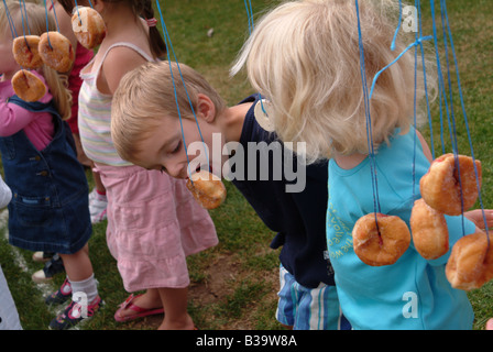 Children eating doughnuts off a string Stock Photo