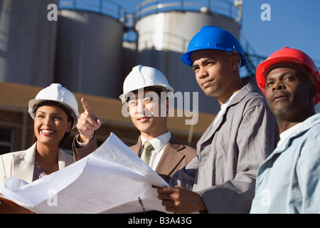 Multi-ethnic businesspeople and construction workers wearing hardhats Stock Photo