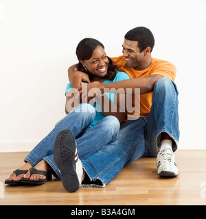 Happy smiling African American couple sitting on floor snuggling Stock Photo