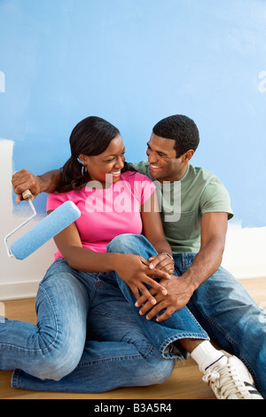 African American couple relaxing together next to half painted wall Stock Photo