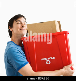 Portrait of smiling Asian young man holding recycling bin Stock Photo