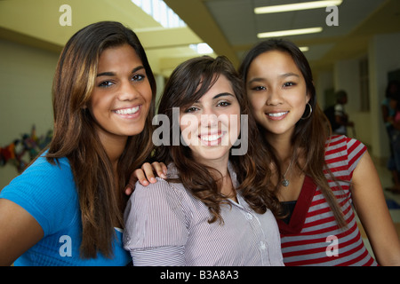 Multi-ethnic teenaged girls hugging in school hallway Stock Photo