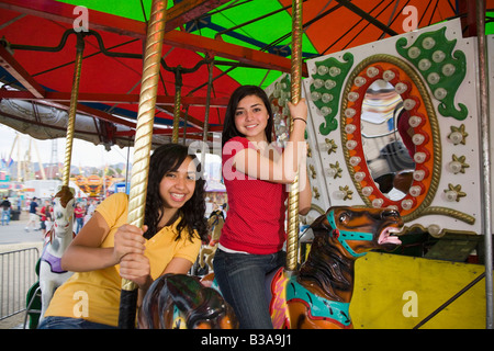 Mixed Race teenaged girls on carousel horse Stock Photo
