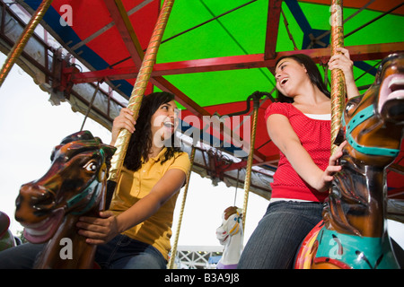 Mixed Race teenaged girls on carousel horse Stock Photo
