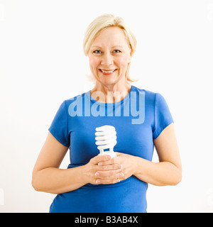 Portrait of smiling adult blonde woman holding energy saving lightbulb Stock Photo
