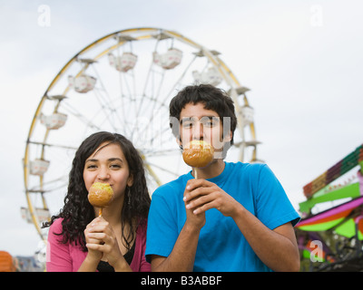 Multi-ethnic teenaged couple eating candied apples Stock Photo