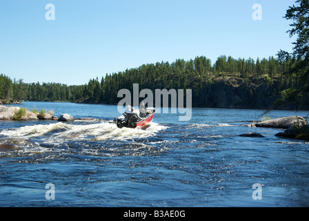 Fishing guide with anglers running small rapids in an aluminum boat on Gammon River Stock Photo