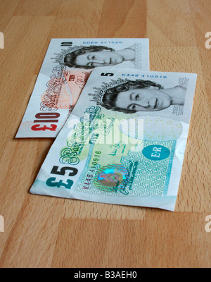 A £5 and £10 note ( Sterling ) laid out on a beech table. Stock Photo