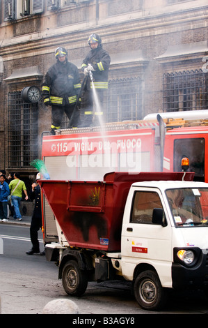 Two firefighters putting out a fire on a truck in Rome, Italy Stock Photo