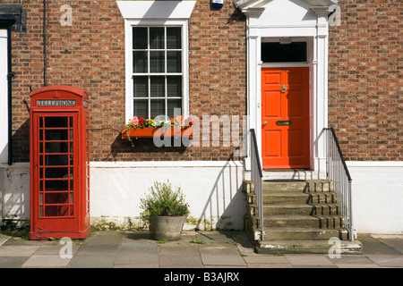 UK Cheshire Tarporley High Street K6 phone box outside former post office near red painted front door Stock Photo