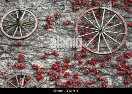 Cart wheels hanging on pub stone wall Stock Photo
