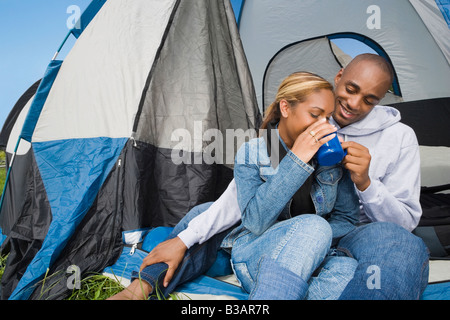 African couple drinking coffee at campsite Stock Photo