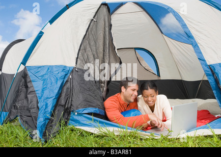 Hispanic couple looking at laptop in tent Stock Photo