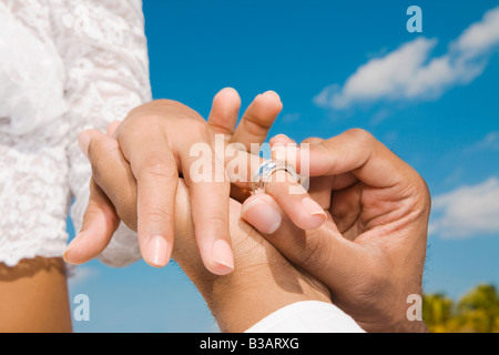 African groom putting ring on bride’s finger Stock Photo