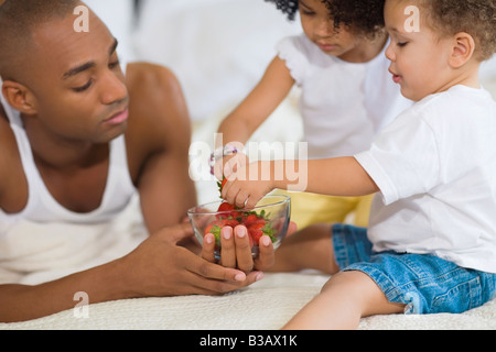 African father and children eating fruit Stock Photo