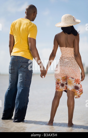 Multi-ethnic couple holding hands at beach Stock Photo