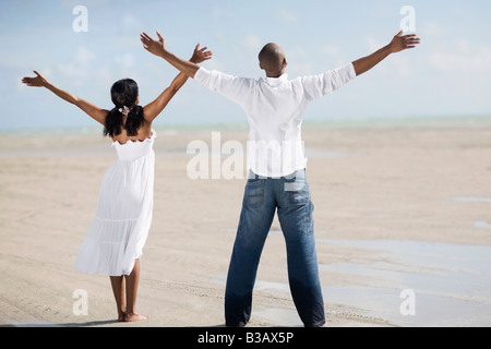 Multi-ethnic couple with arms raised at beach Stock Photo