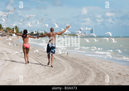 Multi-ethnic couple holding hands at beach Stock Photo