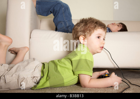 Boy Playing Video Games, Brother Lying on Sofa Stock Photo
