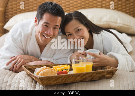 Asian couple eating breakfast in bed Stock Photo