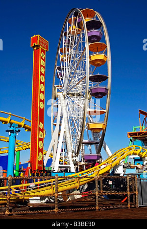 Pacific Park, Santa Monica CA pier family amusement park large Ferris wheel Roller Coaster moving over the ocean Vertical Stock Photo