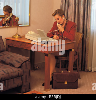 Business woman conversing on 'phone in hotel room. Stock Photo