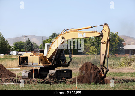 Photo of a large excavator tracked backhoe working and helping to build a new home. Construction equipment. Stock Photo