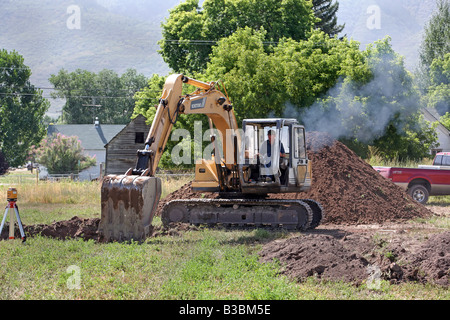 Photo of a large excavator tracked backhoe working and helping to build a new home. Construction equipment. Stock Photo