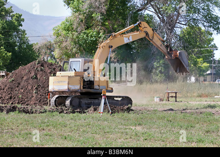 Photo of a large excavator tracked backhoe working and helping to build a new home. Construction equipment. Stock Photo