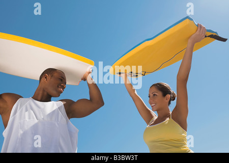 Multi-ethnic couple holding bodyboards Stock Photo