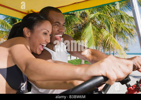 Multi-ethnic couple driving pedal cart Stock Photo