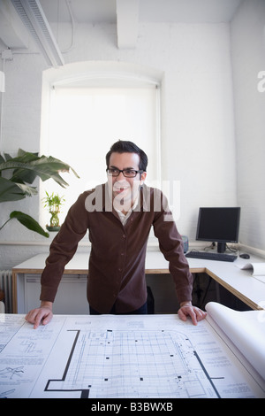 Hispanic businessman leaning on blueprints Stock Photo
