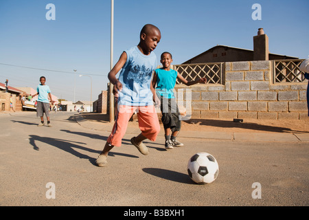 african boys playing soccer in the street Stock Photo