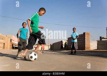 african boys playing soccer in the street Stock Photo