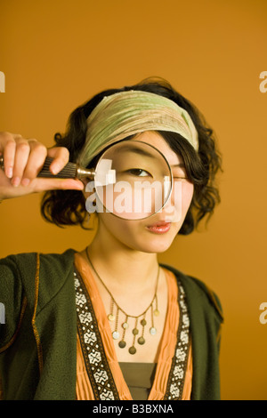 Asian woman looking through magnifying glass Stock Photo
