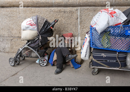 Homeless Chinese man sleeping next to his belongings in the Chinatown area by the Manhattan Bridge in New York City Stock Photo