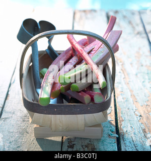 Rhubarb in a wooden basket on a wooden floor Stock Photo